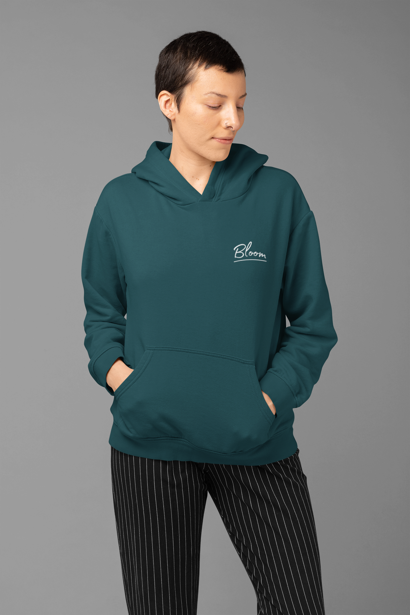 Person wearing a teal hoodie with a logo on a gray background