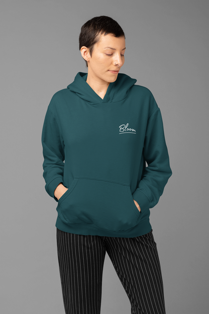 Person wearing a teal hoodie with a logo on a gray background